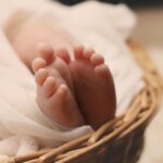 a new born baby is in a basket and has her toes showing through a blanket