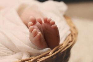 a new born baby is in a basket and has her toes showing through a blanket